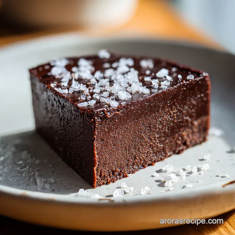 Neatly cut squares of rich, dark chocolate fudge sit on a plate, dusted with cocoa powder for a rustic, elegant dessert.