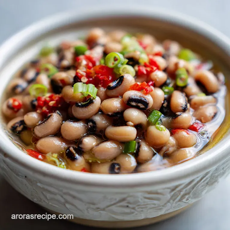 Elegant white bowl filled with creamy black-eyed peas, garnished with a swirl of olive oil and a sprig of bright green par...