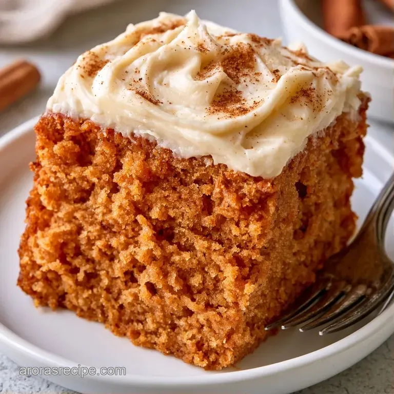 A slice of cinnamon-hued cake on a white plate, topped with creamy icing and a fresh raspberry garnish.