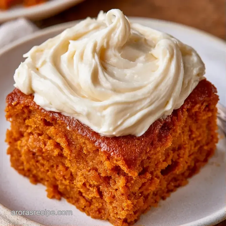 Slice of vibrant orange cake on a white ceramic plate, topped with swirls of white cream and a dust of cinnamon.